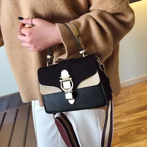 Detail of trendy color-block crossbody bag with D-shaped gold buckle and striped strap