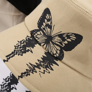 Close-up of beige canvas bucket hat featuring black butterfly print and twill texture