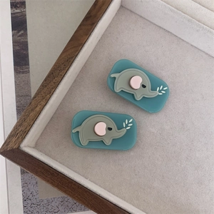 Close-up of two cute acetate elephant hair clips with blue rectangular bases and grey motifs