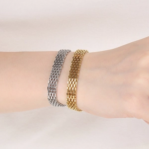 Gros plan de bracelets en maille dorée et argentée portés par un mannequin sur tissu