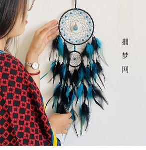 Detail of bohemian double-ring dreamcatcher with blue pendant and peacock blue feathers