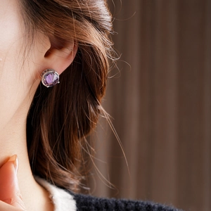 Close-up of 18k gold plated sterling silver stud with purple zircon on model's ear