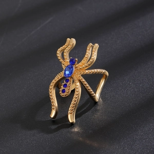 Détail macro d'une bague araignée gothique dorée avec cristal bleu profond scintillant