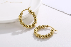 Macro view of gold-plated beaded hoop earrings featuring polished metallic spheres