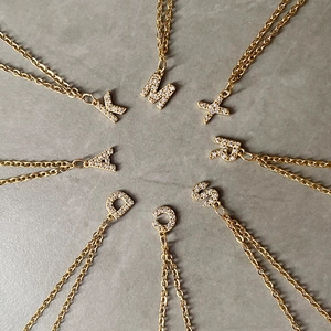 Macro view of crystal paved letter pendants on gold plated stainless steel necklaces
