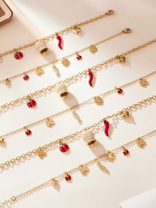 Vue détaillée de bracelets à breloques dorés avec cloches en zircon et pendentifs piment