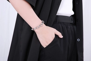 Close-up of a chunky silver titanium steel chain bracelet worn on a female wrist