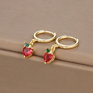 Macro shot of strawberry earrings with red heart stones and green leaves in gold finish