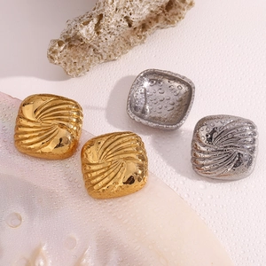Detailed macro view of square 18K gold and silver earrings with spiral ripple textures