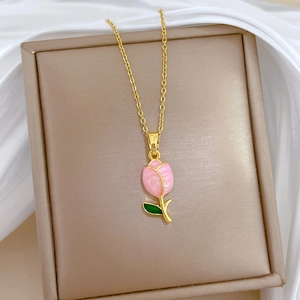 Close-up of a golden tulip necklace with pink petals and green leaves in a jewelry box