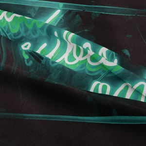 Macro shot of bohemian tapestry fabric with neon green waves and white script print