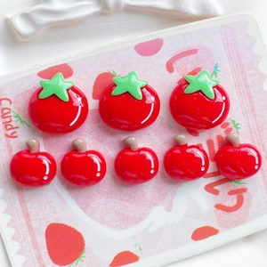 Macro detail of glossy red resin tomato and cherry DIY charms for jewelry making