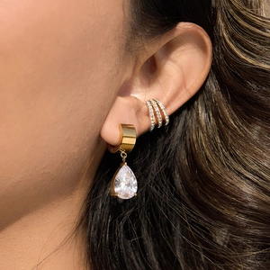 Vue macro de créoles dorées en acier inoxydable avec zircons et bague d'oreille chic