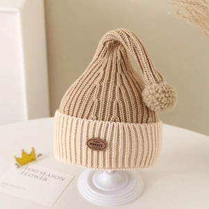 Detail of baby winter knit beanie with soft pompom and brown leather brand label