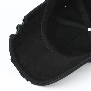 Close-up of distressed brim details and reinforced stitching on black cotton baseball cap