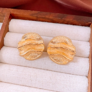 Detailed macro view of 18k gold plated textured round stud earrings on a velvet display