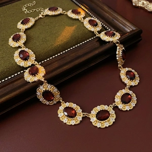 Detail of vintage gold necklace with oval red gemstone and white enamel floral accents