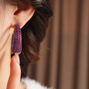 Macro shot of vintage silver needle C-shaped earrings with fuchsia pave-set zircons
