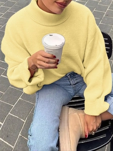 Dettaglio del maglione giallo a collo alto con vestibilità ampia e trama in maglia pregiata