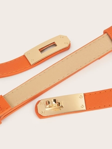 Detail of orange cross-grain slim belt with iconic golden metal swivel lock buckle
