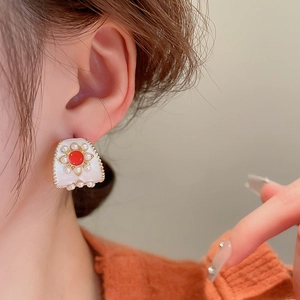 Gros plan d'une boucle d'oreille rétro avec pierre rouge et perles sur l'oreille