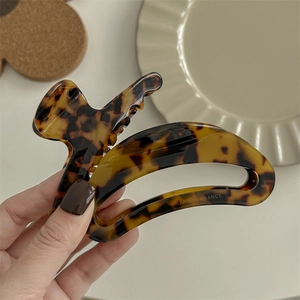 Large tortoiseshell acetate hair claw clip held by hand for elegant hair styling