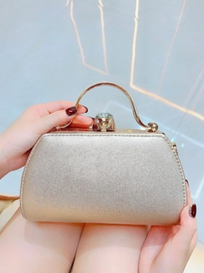 Detailed close-up of golden evening handbag with diamond lock and metal handle