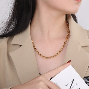 Polished gold titanium steel O-chain necklace worn by a model in a beige suit