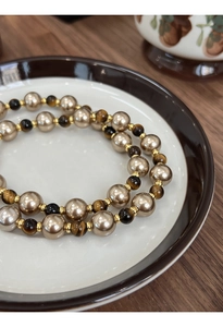 Détail d'un collier vintage avec perles champagne, pierres œil de tigre et perles d'or
