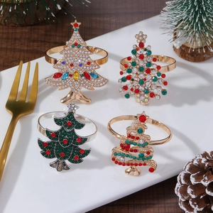 Four vintage Christmas tree napkin rings with colorful crystals on a white ceramic plate