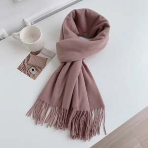 Close-up of pink cashmere-like scarf texture with elegant fringed edges on a clean desk