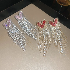 Macro shot of silver and red heart rhinestone fringe earrings on a beige display
