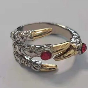 Detail of silver dragon claw ring with golden accents and red gemstones in punk style