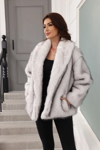 Detailed view of white faux fur coat with large lapel and fluffy texture in a modern style