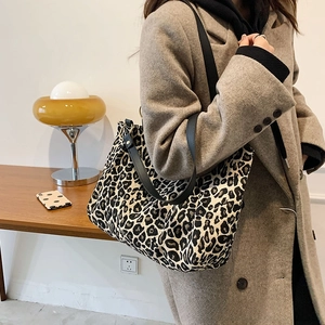 Detailed close-up of a leopard print canvas tote bag with black wide shoulder strap