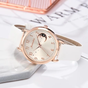 Detail view of quartz watch with moon pattern dial on white marble stone