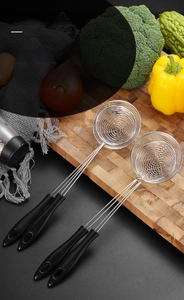 Detail of stainless steel wire skimmers with heat-resistant handles on wooden board