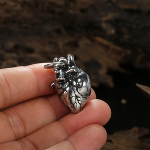 Vintage silver anatomical heart pendant necklace in stainless steel held by fingers