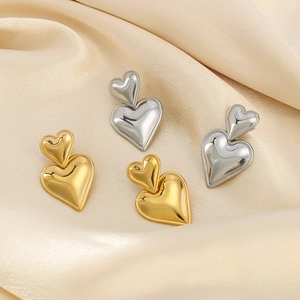 Double heart drop earrings in 18K gold and silver finish on silk background