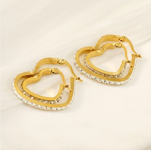 Detail of 18k gold heart earrings with sparkling crystals on soft white fabric
