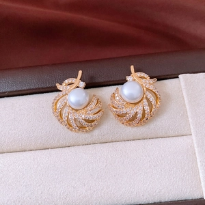 Macro detail of 18k gold plated feather earrings with pearl and shimmering cubic zirconia