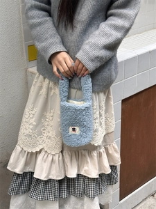 Light blue faux fur tote bag with a cartoon cat patch being held by a model
