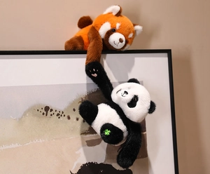 Detail of cute plush panda and red panda hanging on a frame with fine embroidery work