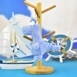 Close-up detail of a cute blue plush dinosaur keychain charm hanging on a wooden display stand