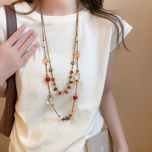 Detail of vintage layered beaded necklace with amber and red floral crystal pendants