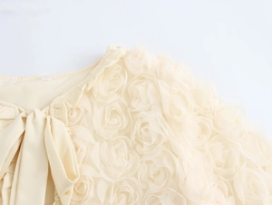 Detail of cream cardigan featuring a large decorative bow and 3D mesh floral embroidery