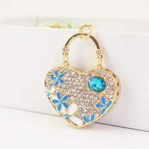 Sparkling heart keychain with blue gemstones and enamel flowers on gold metal