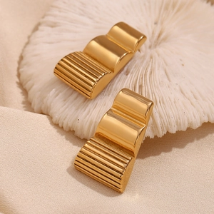 Detailed view of long trapezoidal earrings with wave pattern and 18K gold plated texture