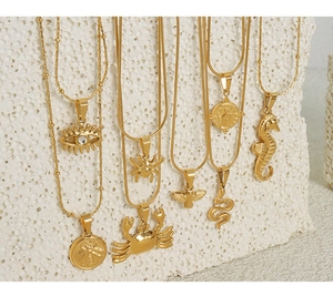 Close-up of gold geometric animal pendants including snake and spider on stony background