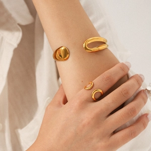 Polished gold asymmetric water drop bracelet and open ring set on a model